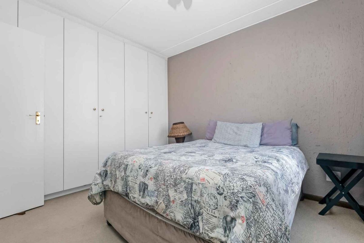 A bedroom featuring built-in floor-to-ceiling wardrobes and a textured accent wall.