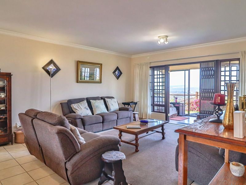 Spacious living room featuring tiled and carpeted flooring, with large sliding glass doors providing access to an outdoor balcony area.