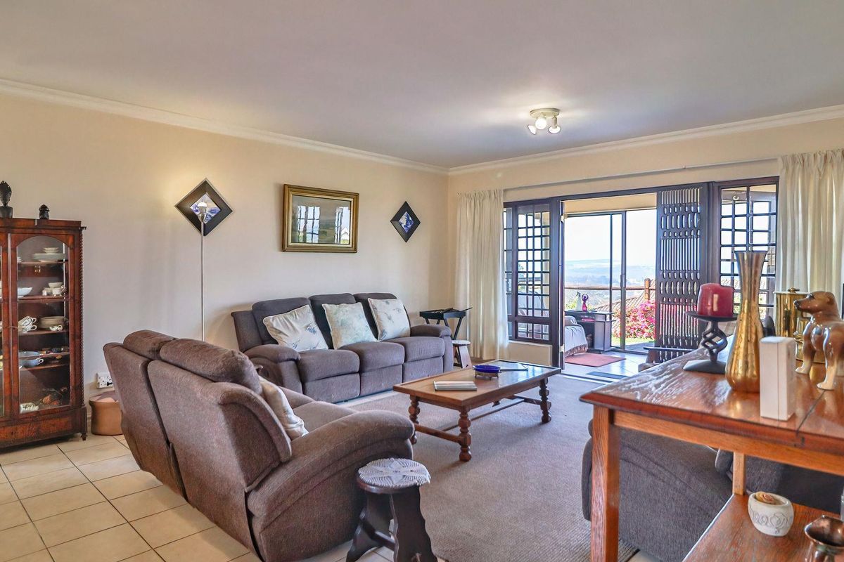Spacious living room featuring tiled and carpeted flooring, with large sliding glass doors providing access to an outdoor balcony area.