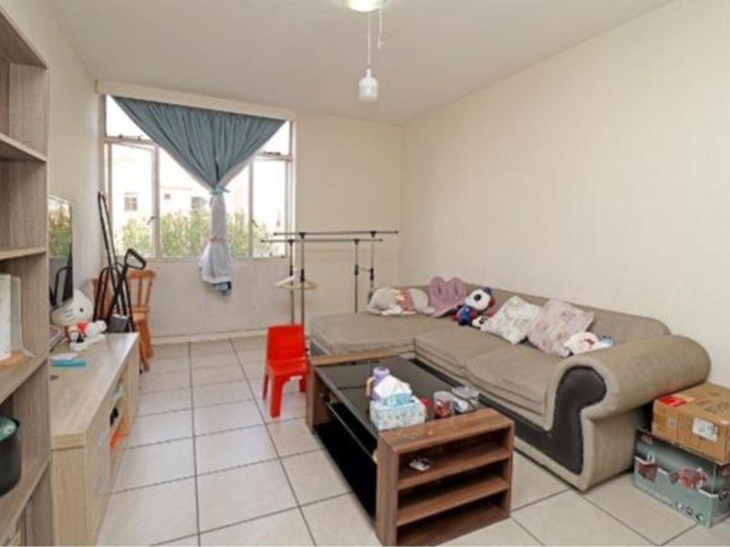 A functional living room featuring tiled flooring and a large window, providing natural light to the space.