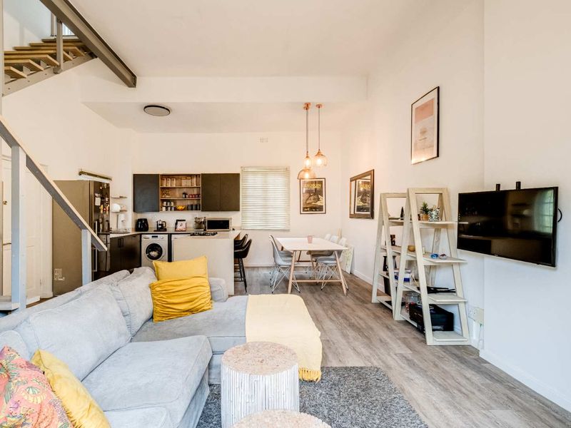 Modern open-plan living area featuring a contemporary kitchen, dining space, and a staircase leading to an upper level with durable laminate flooring throughout.
