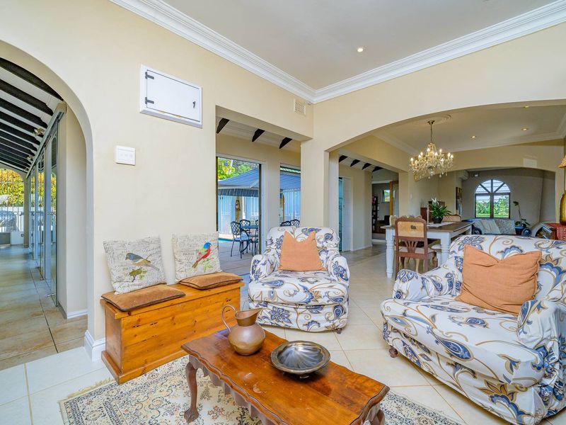 Spacious open-plan living area featuring elegant archways, crown molding, and tiled flooring, with seamless flow to the dining space and outdoor patio.