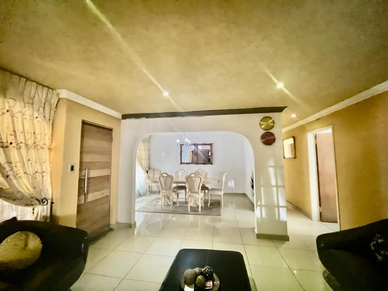 Open plan living and dining area featuring tiled flooring, recessed lighting, and a central archway connecting the spaces.