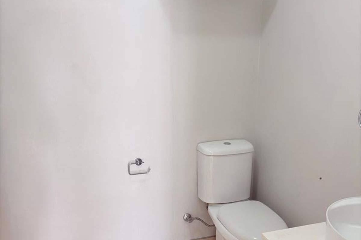 A clean and functional bathroom featuring a modern vanity with basin, a standard toilet, and a louver window for ventilation.