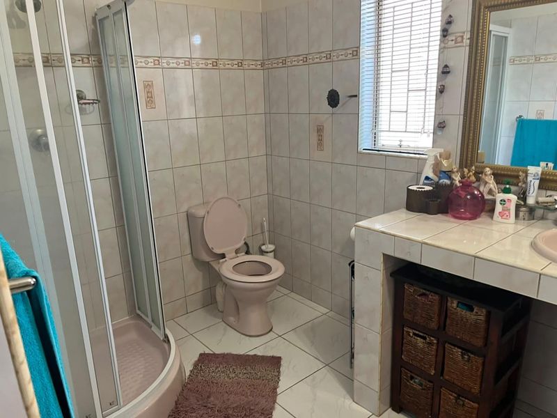 A functional bathroom featuring a shower enclosure, toilet, and a tiled vanity with a built-in basin.