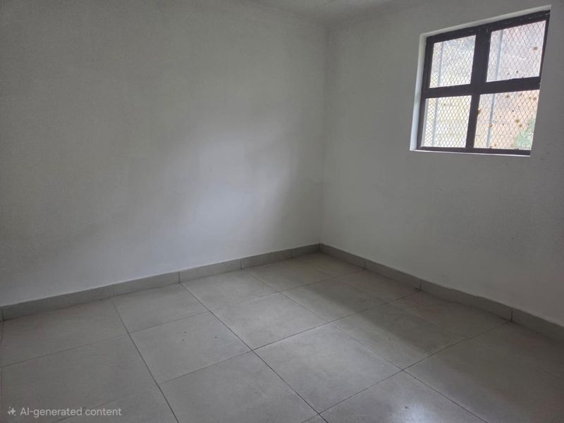 A simple, empty bedroom featuring neutral tiled flooring and a window with a security grille.