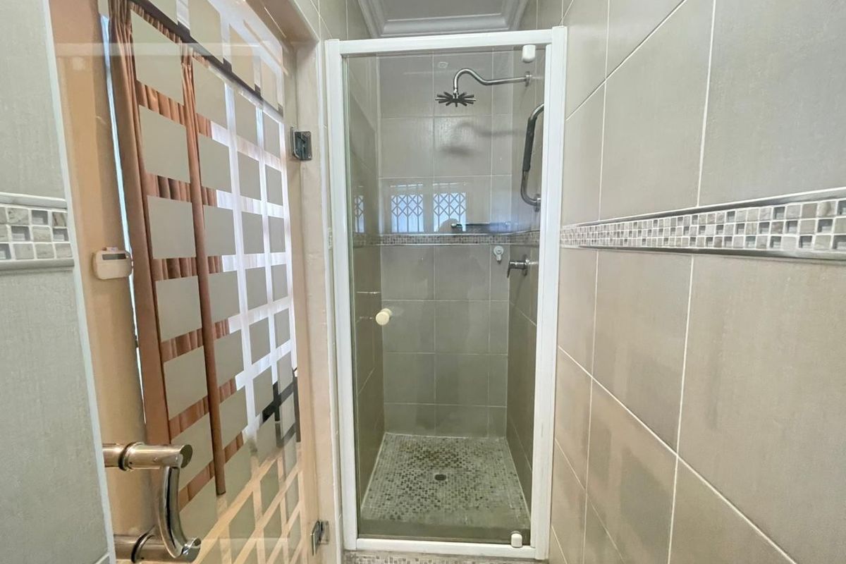 A compact bathroom featuring a tiled shower enclosure with a glass door and modern shower fixtures.