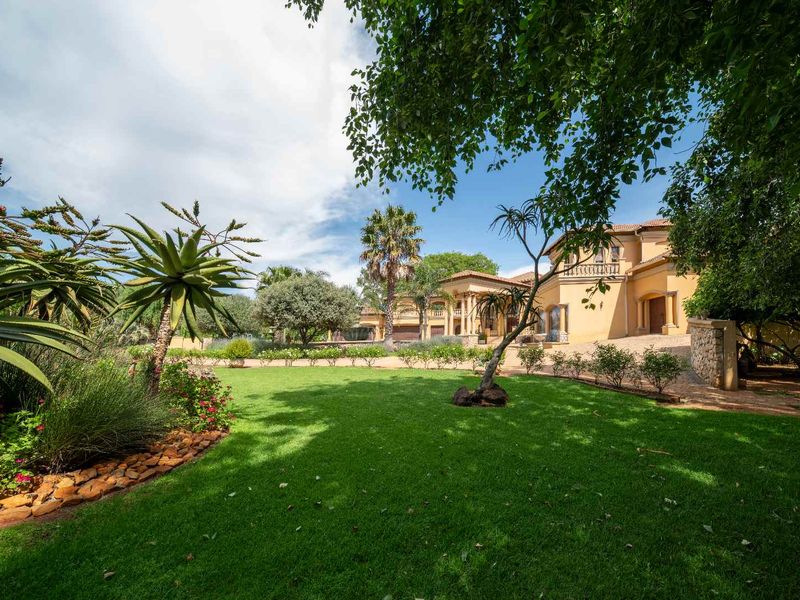 A well-maintained front garden and driveway leading to a large, multi-story residential property with a covered entrance.