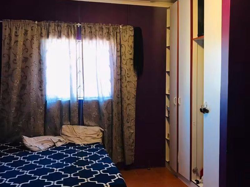 A bedroom featuring tiled flooring and a built-in wardrobe with integrated shelving.