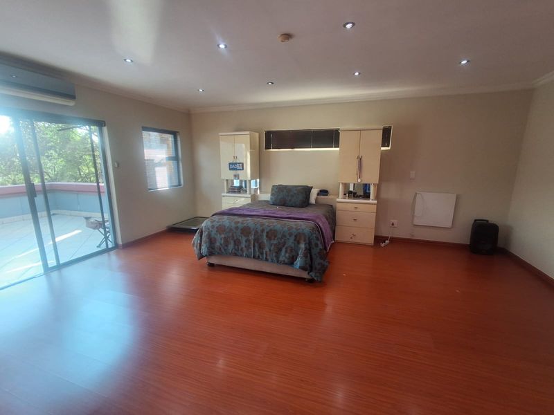 Spacious bedroom featuring laminate flooring, built-in cabinetry, recessed lighting, and a sliding glass door providing access to an outdoor balcony area.