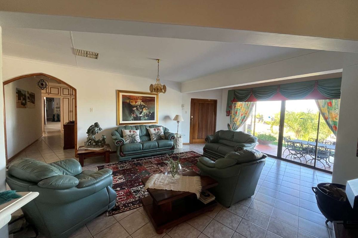 Spacious living room featuring tiled flooring, an arched entryway, and large sliding glass doors that provide access to the outdoor patio area.