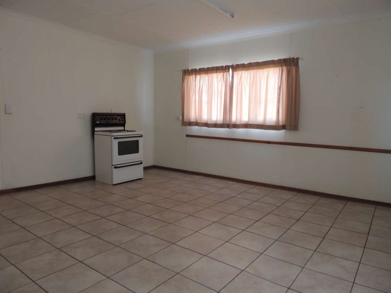 An empty kitchen space featuring tiled flooring and a freestanding stove, offering a blank canvas for renovation and modernization.