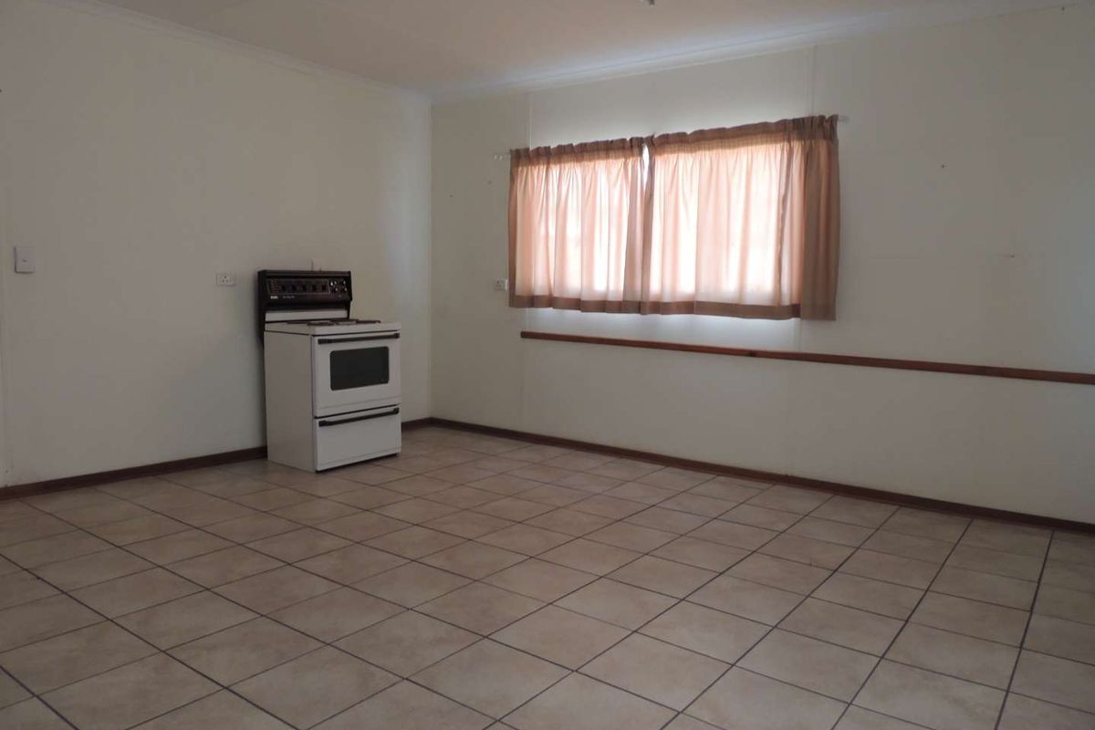 An empty kitchen space featuring tiled flooring and a freestanding stove, offering a blank canvas for renovation and modernization.