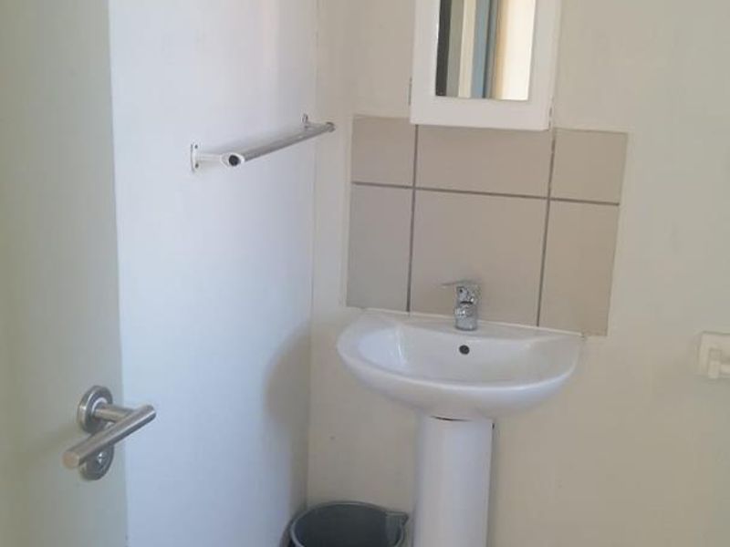 A compact bathroom featuring a pedestal basin, tiled splashback, tiled flooring, and a wall-mounted medicine cabinet.