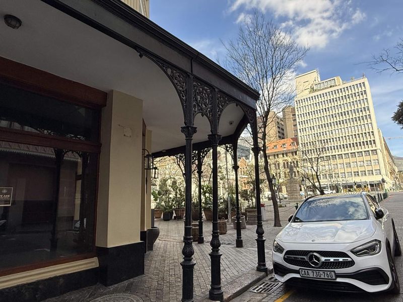 Street-level view of a retail property featuring a classic covered veranda with ornate cast iron columns and large display windows.