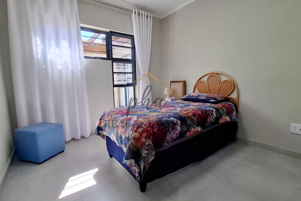 A bright bedroom featuring tiled flooring, neutral wall finishes, and a large window with access to an outdoor area.