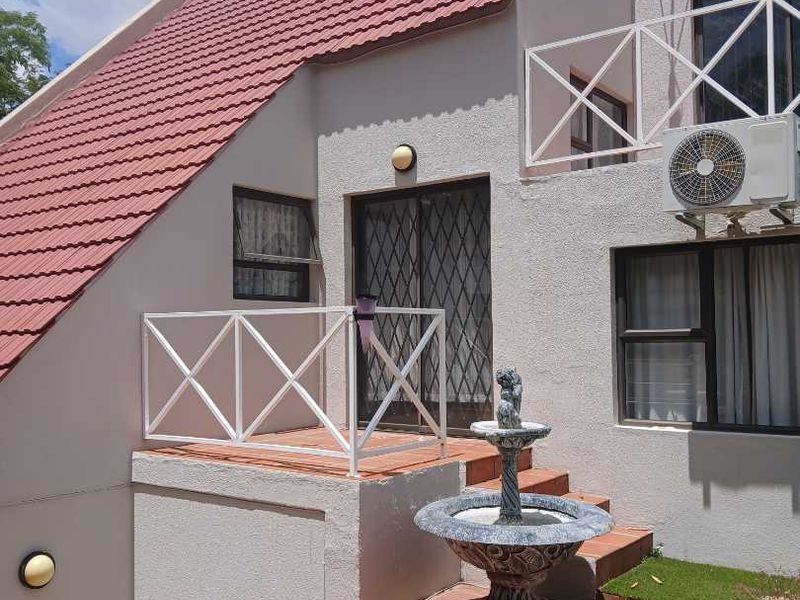 Rear exterior view of the property featuring a terracotta tiled roof, white metal railings, and a staircase leading to a secure entrance.