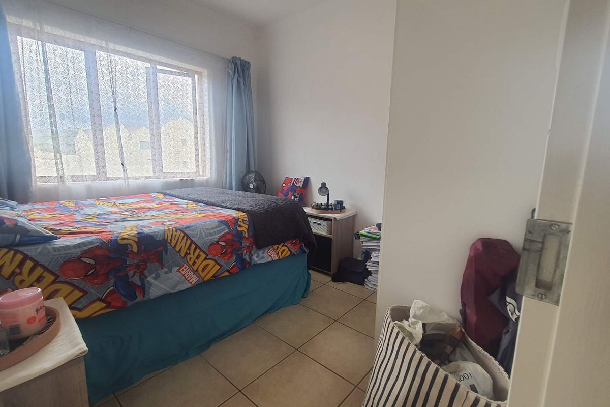 A bedroom featuring tiled flooring and a large window that provides natural light.