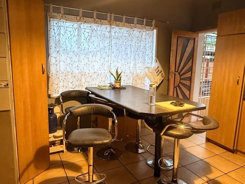 A functional kitchen area featuring tiled flooring, built-in cabinetry, and a central breakfast bar with pendant lighting.