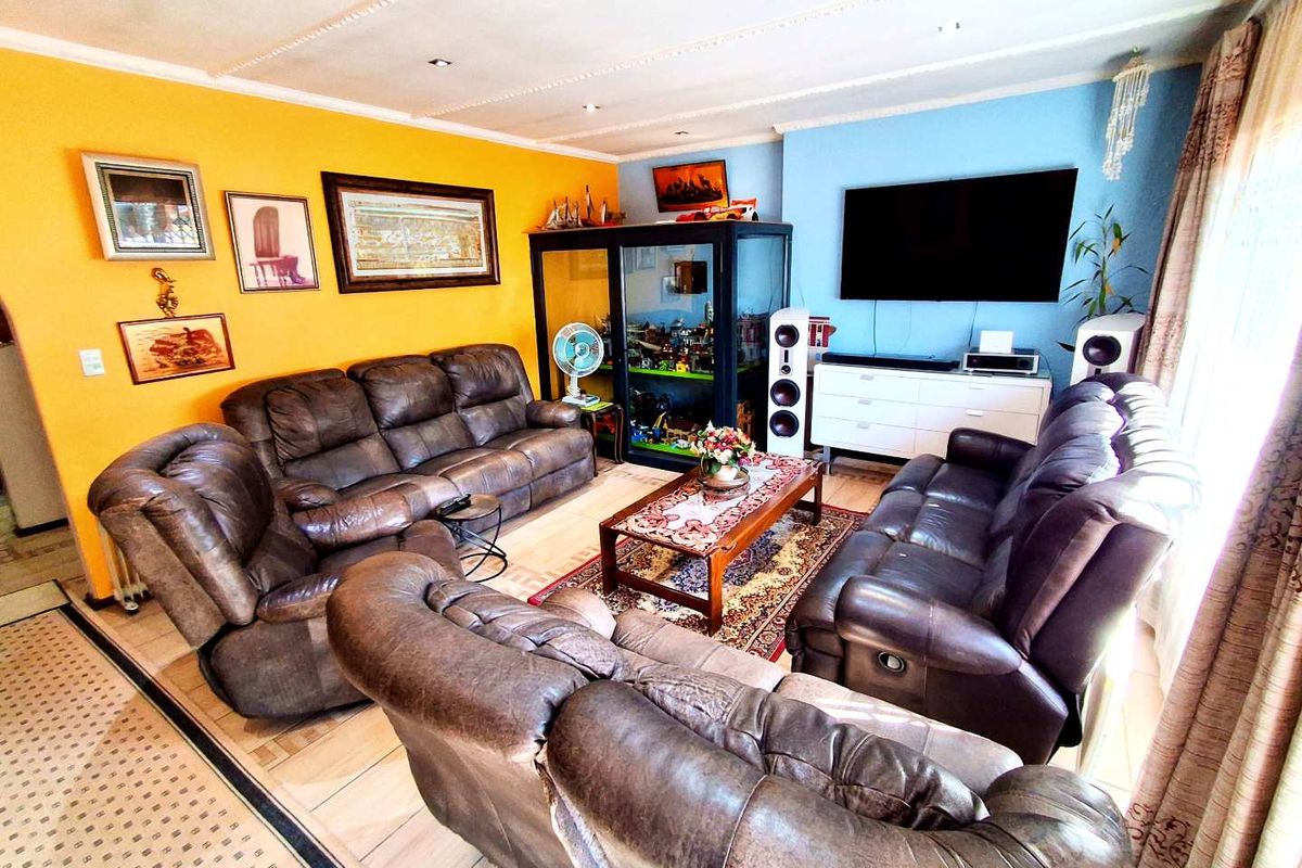 A spacious living room featuring tiled flooring, recessed downlighting, and a coved ceiling, providing a comfortable and functional family entertainment area.