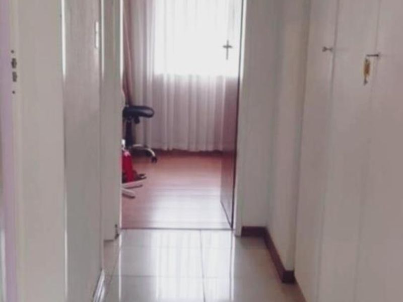 A functional hallway featuring tiled flooring and built-in storage cupboards, leading towards a bedroom area.