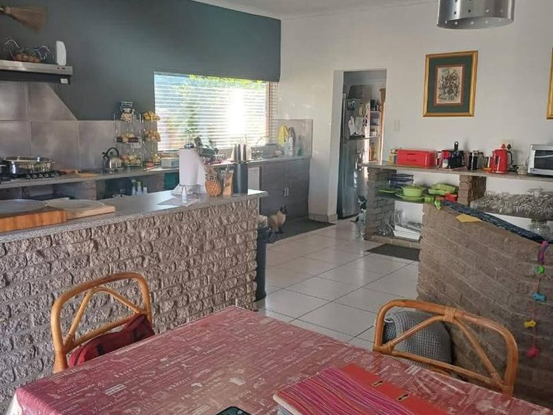 Open-plan kitchen and dining area featuring a brick breakfast bar, tiled flooring, and functional cabinetry, offering a practical layout for daily living.