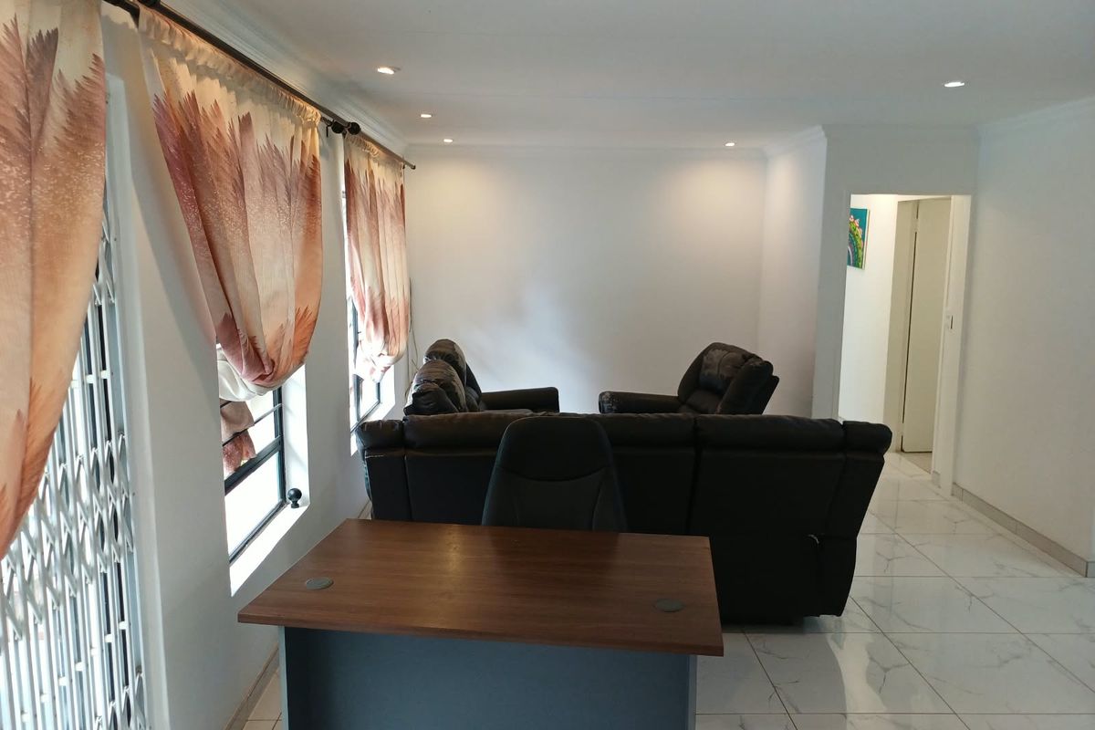 A bright living area featuring modern tiled flooring, recessed downlighting, and decorative cornicing, providing a clean and neutral foundation for interior design.