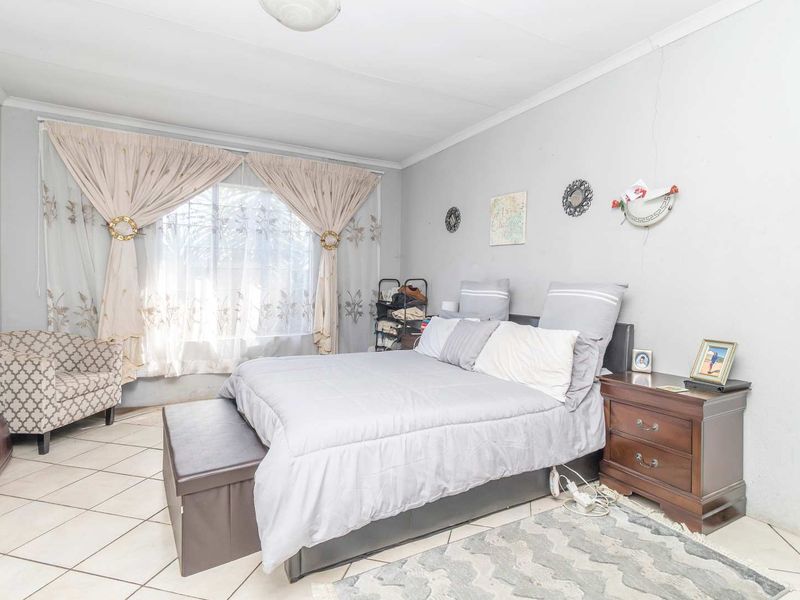 A bedroom featuring tiled flooring and neutral wall finishes, offering a functional space with potential for cosmetic updates.