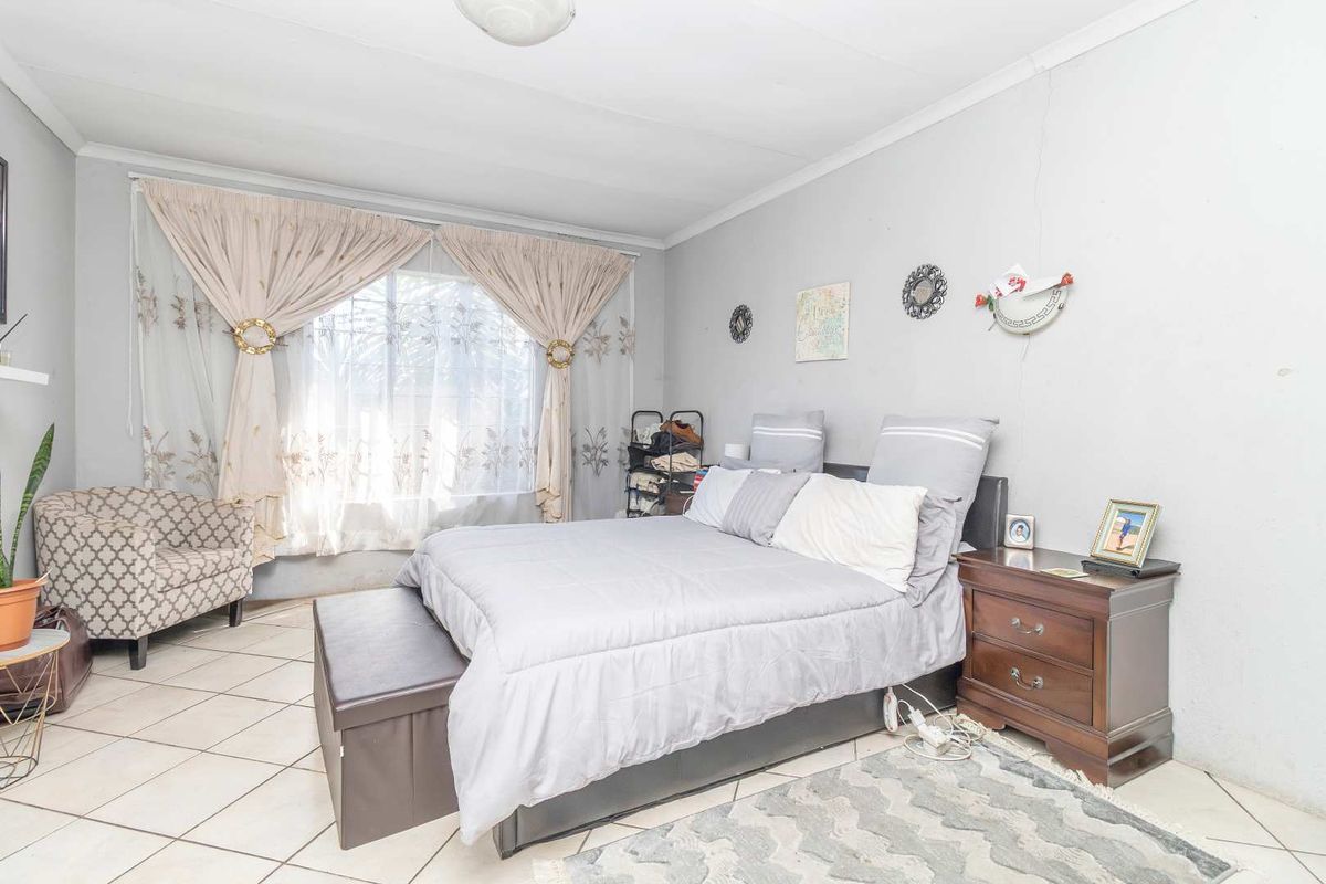 A bedroom featuring tiled flooring and neutral wall finishes, offering a functional space with potential for cosmetic updates.