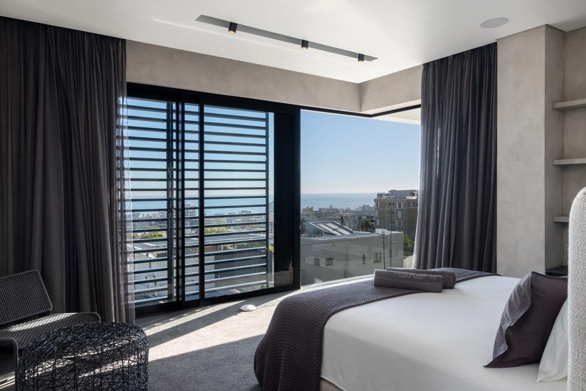Modern bedroom featuring floor-to-ceiling sliding glass doors, built-in shelving, and expansive coastal views.