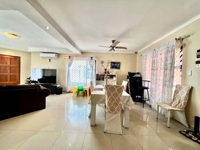 Spacious open-plan living and dining area featuring large format floor tiles, recessed lighting, a ceiling fan, and a wall-mounted air conditioning unit.