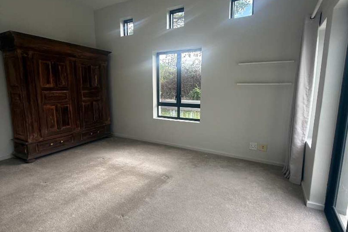 Spacious bedroom featuring neutral carpeting, recessed lighting, and large windows that provide ample natural light and access to an outdoor area.