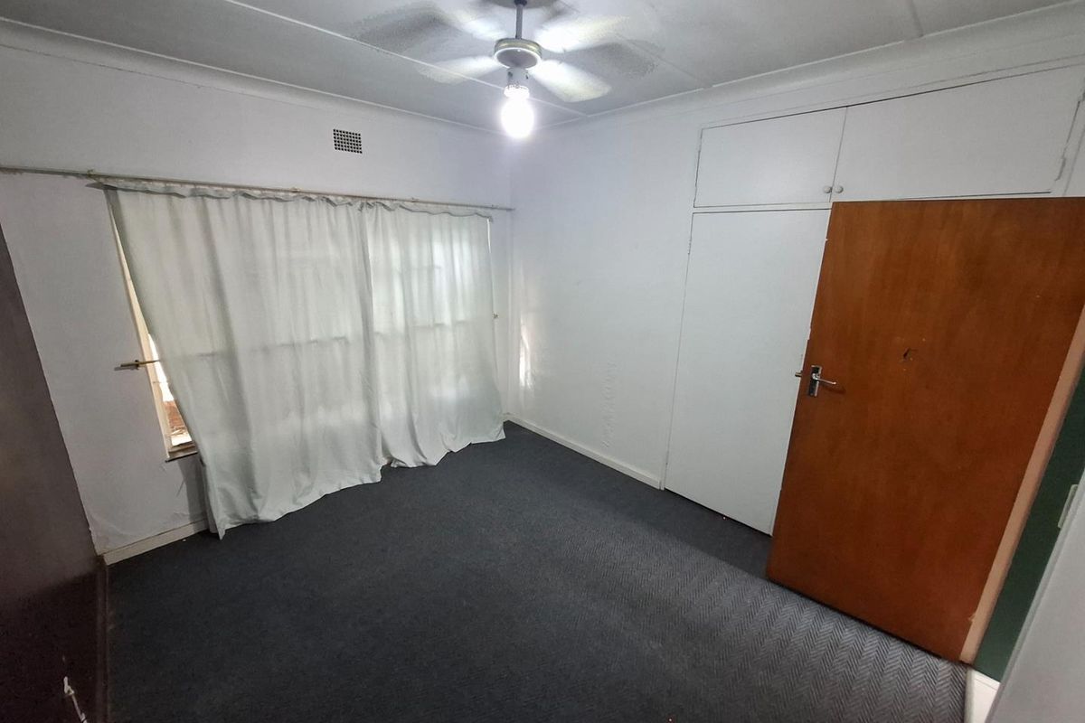 An empty bedroom featuring built-in cupboards, a ceiling fan, and carpeted flooring, offering a blank canvas for personalization.