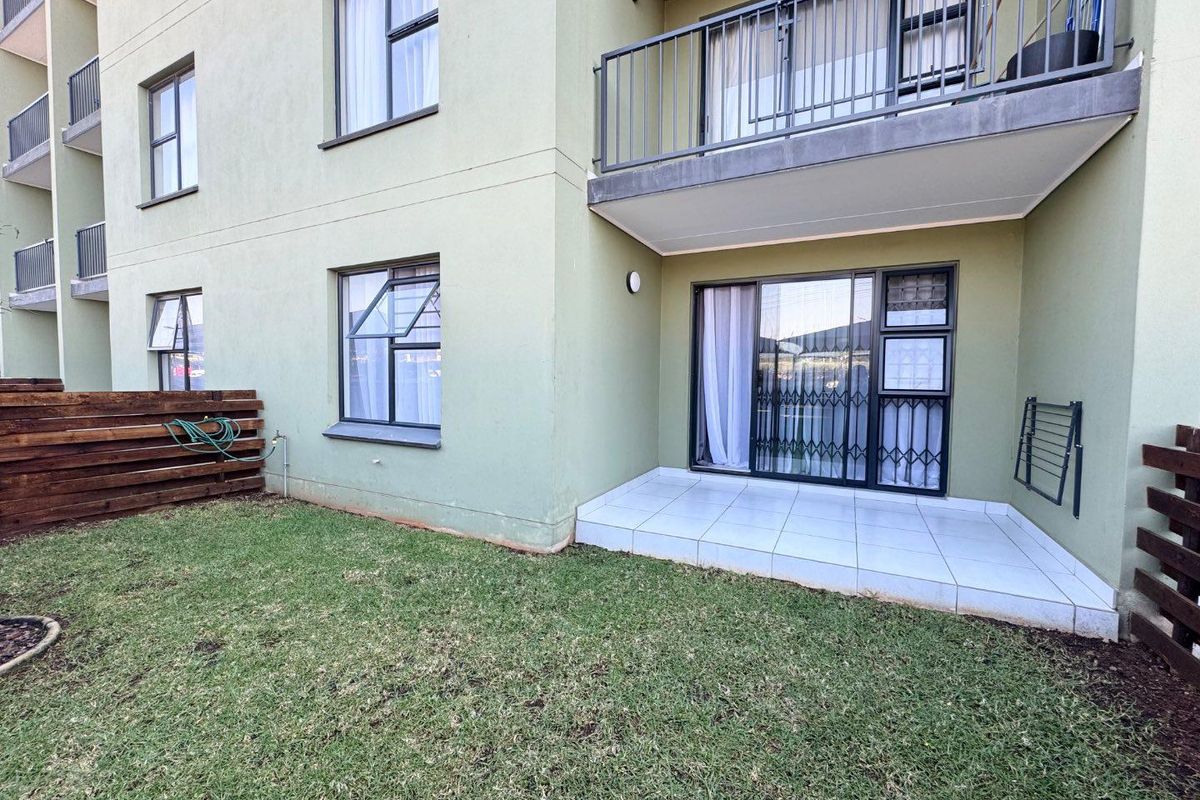 Ground floor apartment exterior featuring a tiled patio, sliding glass doors with security gates, and access to a private lawn area.