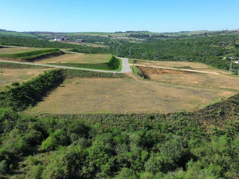 Aerial view of a large, terraced industrial land parcel featuring established access roads and surrounding natural landscape.