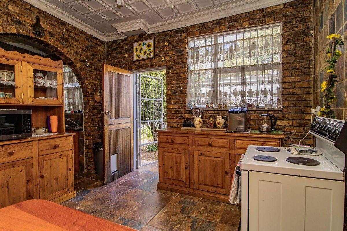 Rustic kitchen featuring exposed brick walls, tiled flooring, a built-in archway, and a freestanding electric stove.