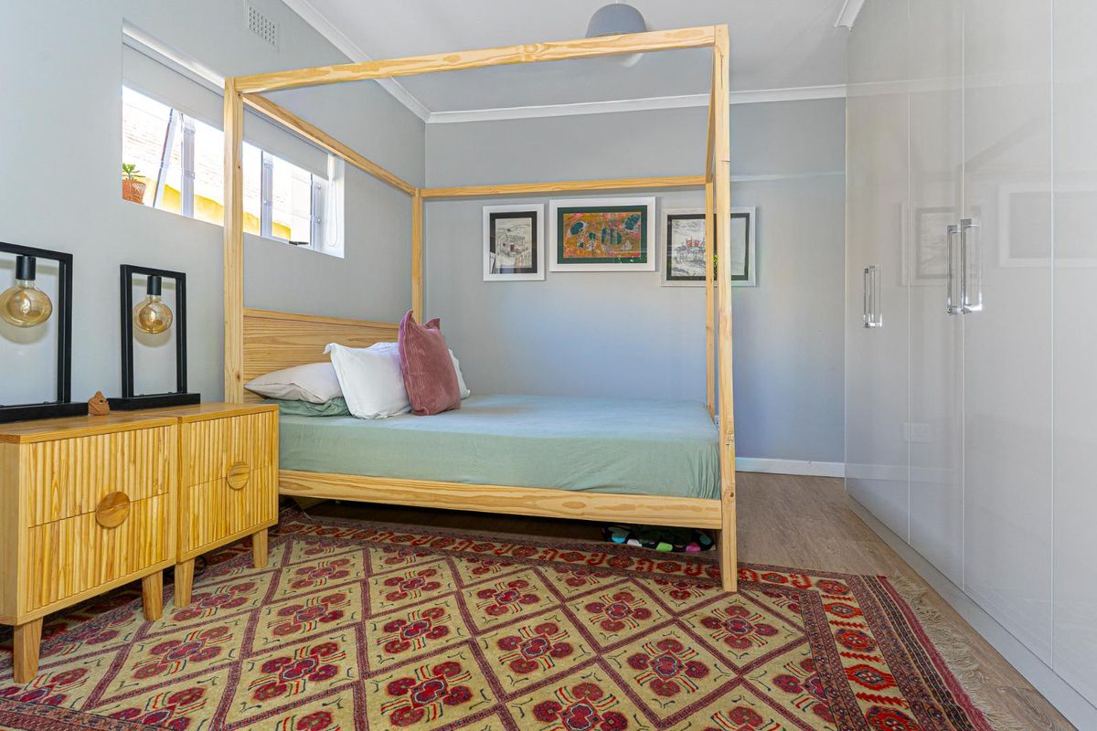 A well-maintained bedroom featuring light wood-look flooring, built-in high-gloss white cabinetry, and clerestory windows providing natural light.