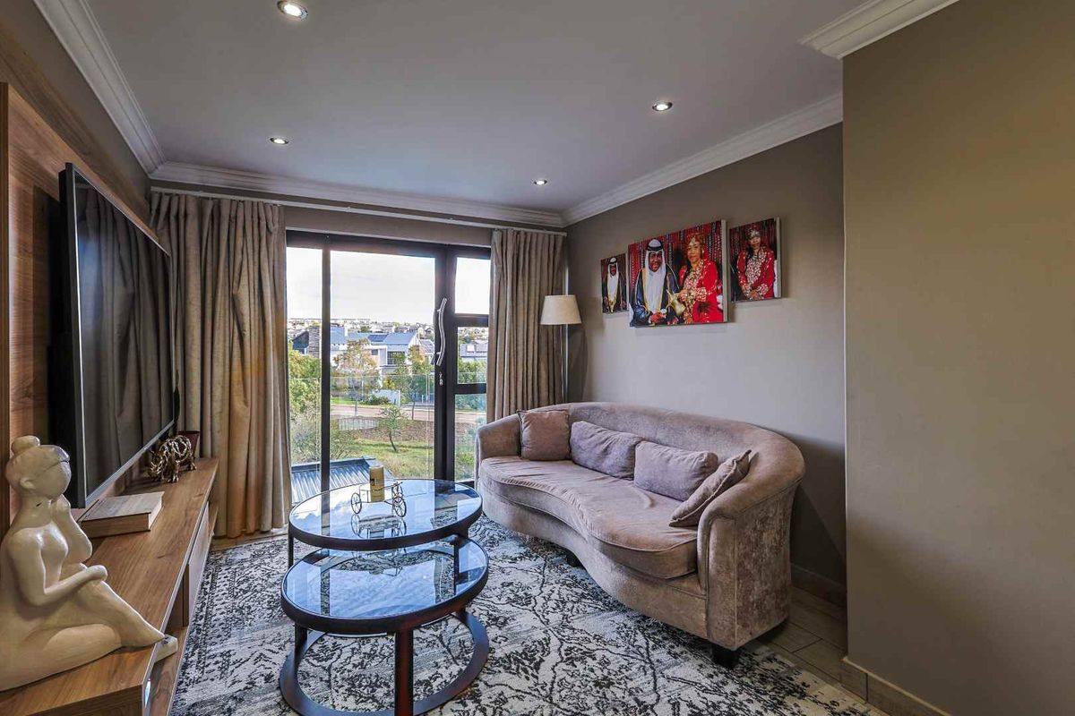 A well-maintained living room featuring recessed ceiling lighting, tiled flooring, and a large sliding glass door providing access to an outdoor balcony.