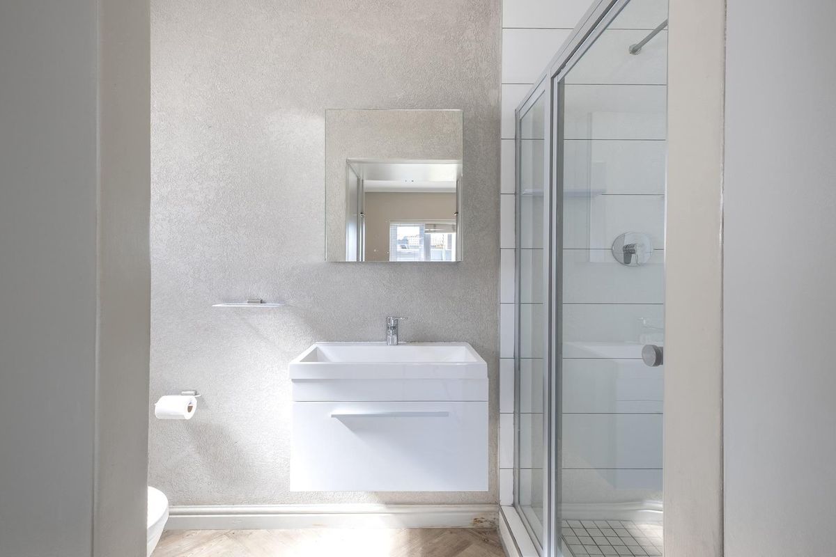 Modern bathroom featuring a wall-mounted vanity, a glass-enclosed shower, and neutral textured wall finishes.