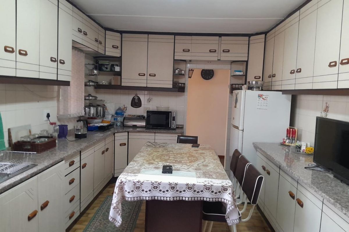 A functional kitchen featuring extensive built-in cabinetry, laminate countertops, and a tiled backsplash, offering ample storage and workspace for daily meal preparation.