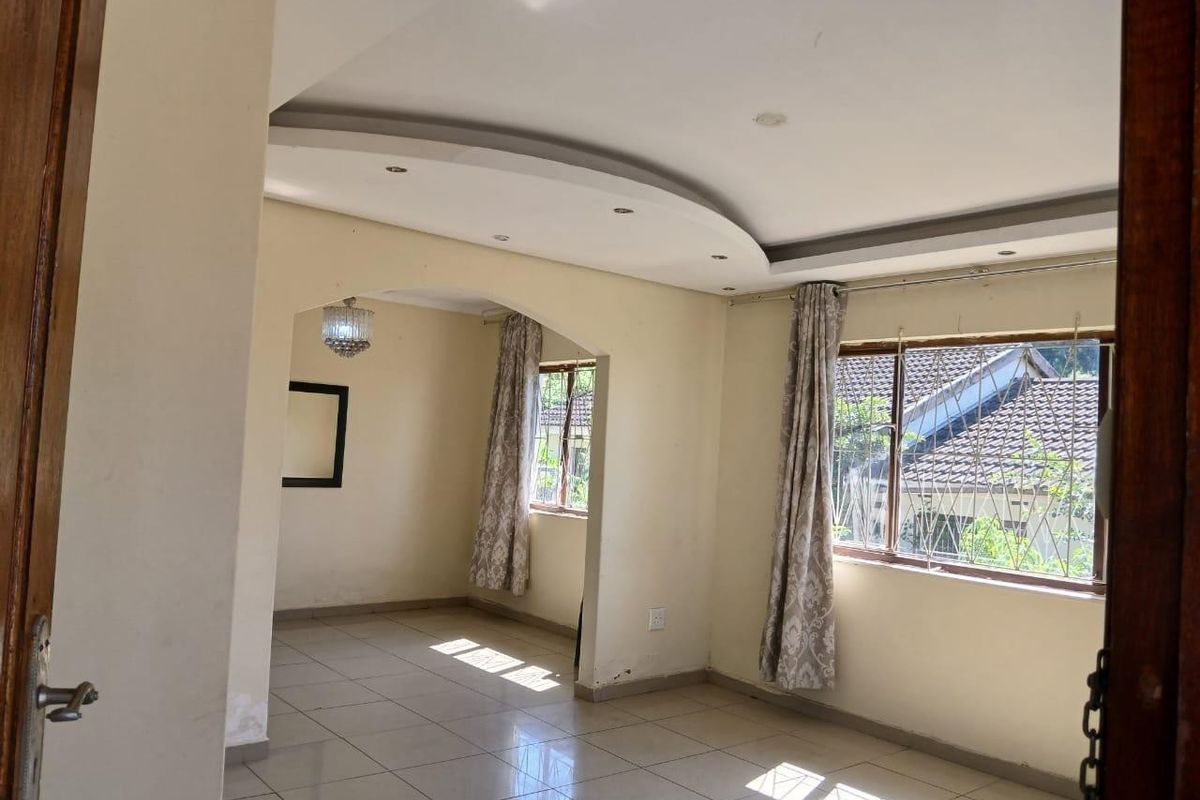 Spacious, light-filled living area featuring tiled floors, a decorative recessed ceiling, and an open-plan layout with an arched transition between spaces.