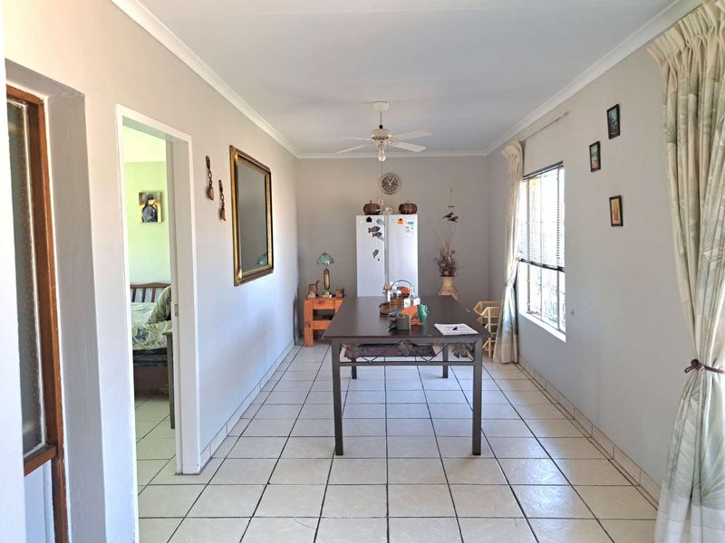 A functional dining area featuring neutral wall tones, tiled flooring, and a ceiling fan, providing a clean and versatile space for family meals.