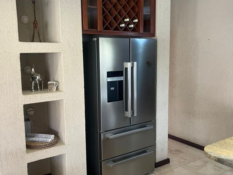 Kitchen area featuring built-in shelving, a wooden wine rack, and stone tile flooring with a textured wall finish.