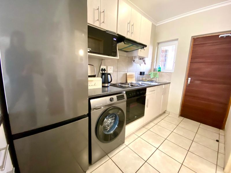 Compact kitchen featuring built-in cabinetry, integrated oven and hob, extractor fan, and tiled flooring with a functional layout.