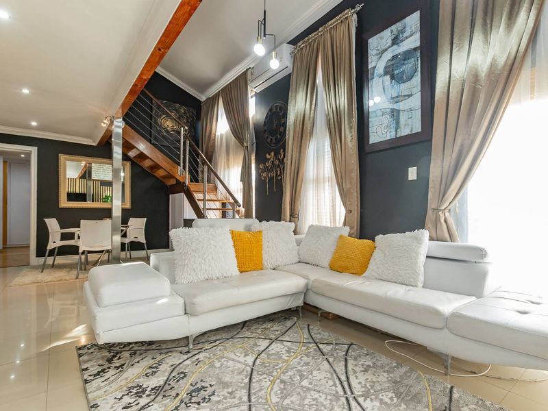 Spacious living room featuring high ceilings, a modern staircase with metal balustrades, tiled flooring, and split-system air conditioning.