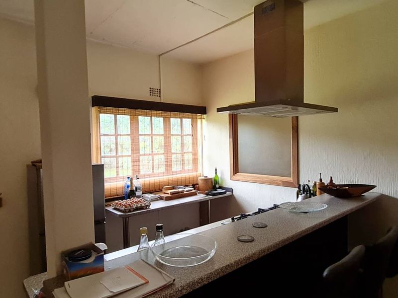 A functional kitchen area featuring a breakfast bar, built-in cabinetry, and a stainless steel extractor fan, providing a practical space for cooking and dining.