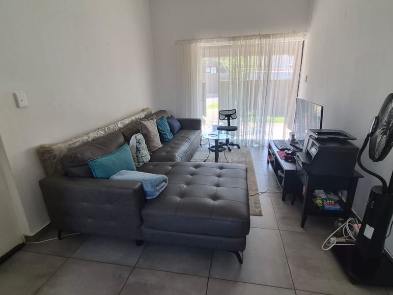 A living room featuring tiled flooring and a sliding glass door providing access to the outdoor area.