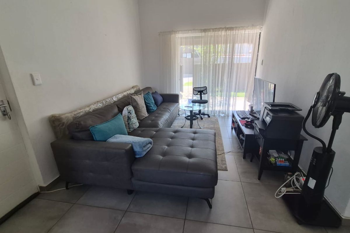 A living room featuring tiled flooring and a sliding glass door providing access to the outdoor area.