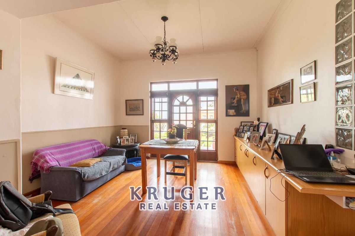 A living room featuring timber flooring, built-in cabinetry, glass block feature wall, and a wooden door leading to the exterior.