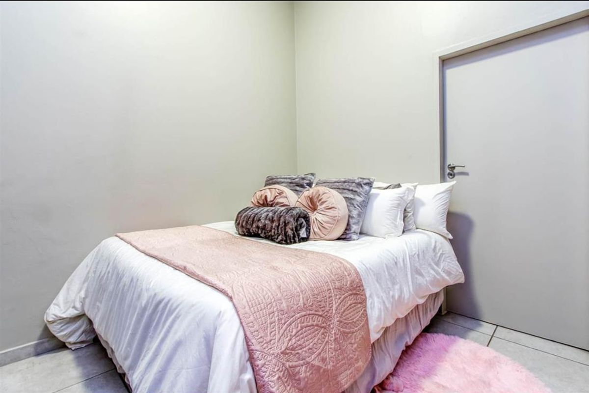 A simple bedroom featuring neutral wall tones, tiled flooring, and a standard interior door.